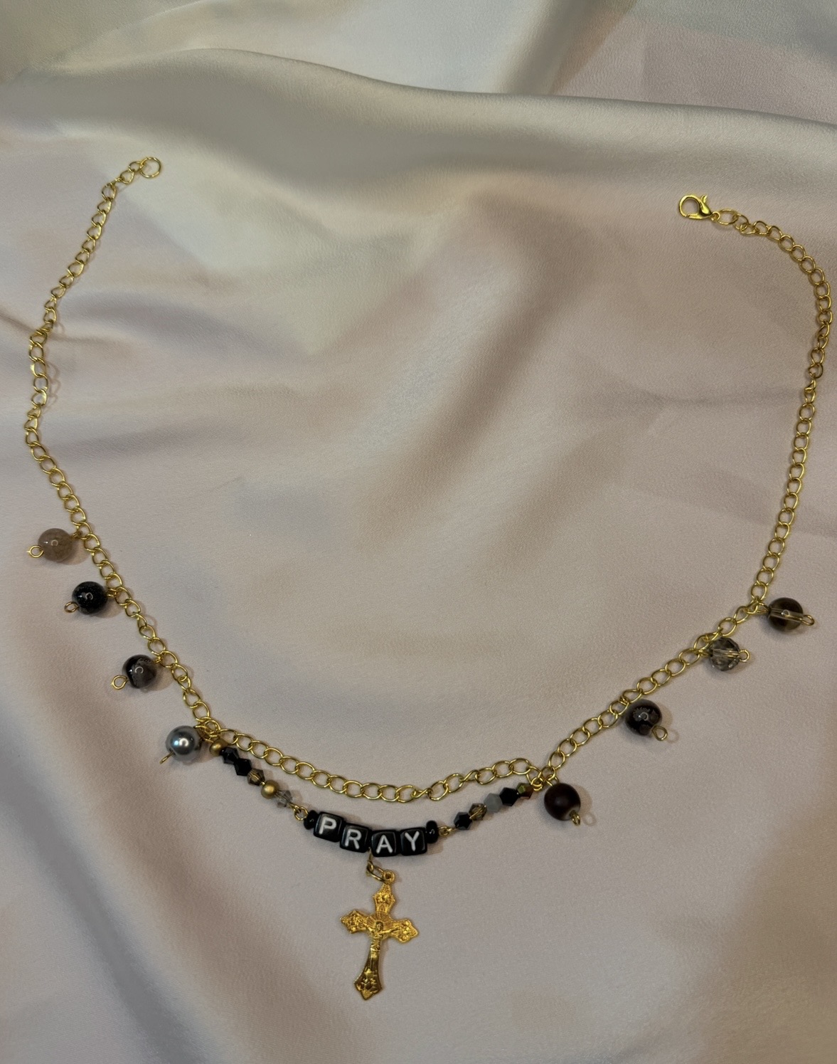 Gold chain necklace with black and white PRAY letter beads and a gold crucifix