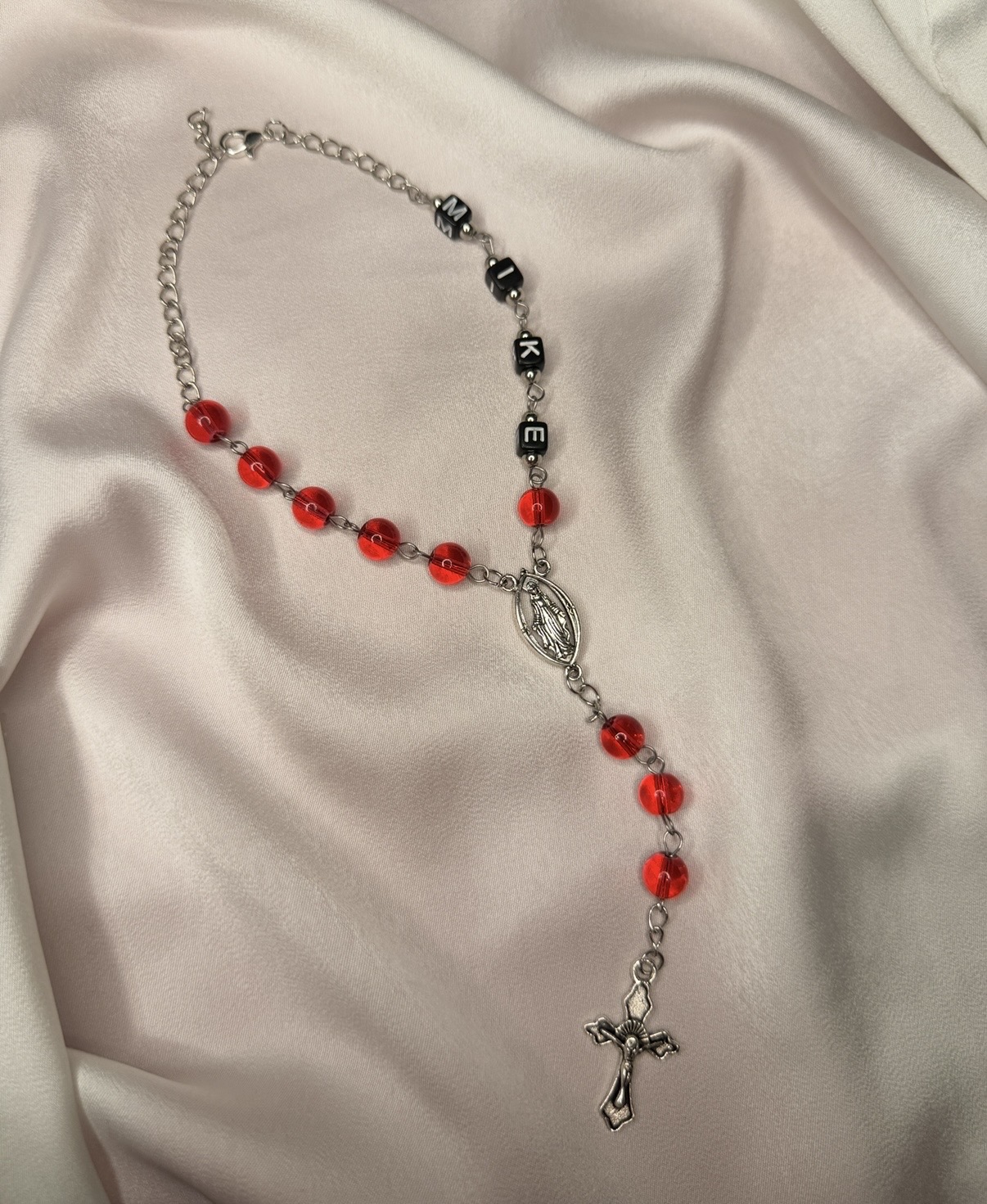Custom red car rosary with black letter beads spelling a name