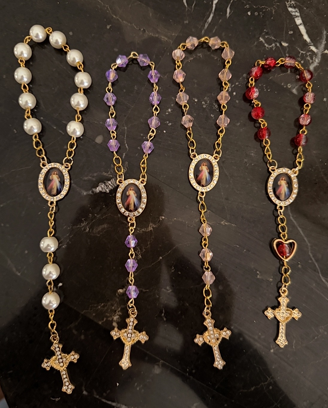 Pocket rosaries in pearl, purple, pink and red laid on marble